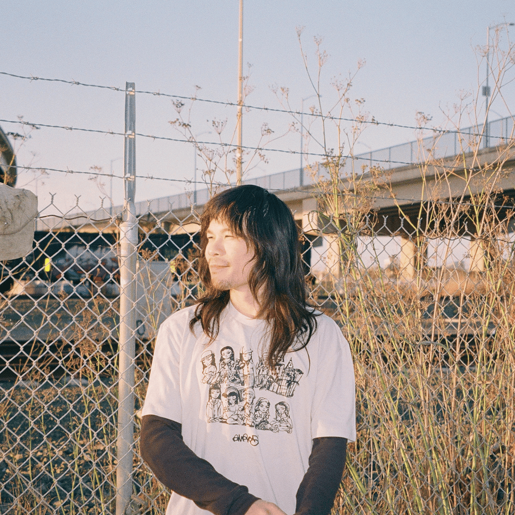 Artist outside wearing Oakland Stroll tee in bone.