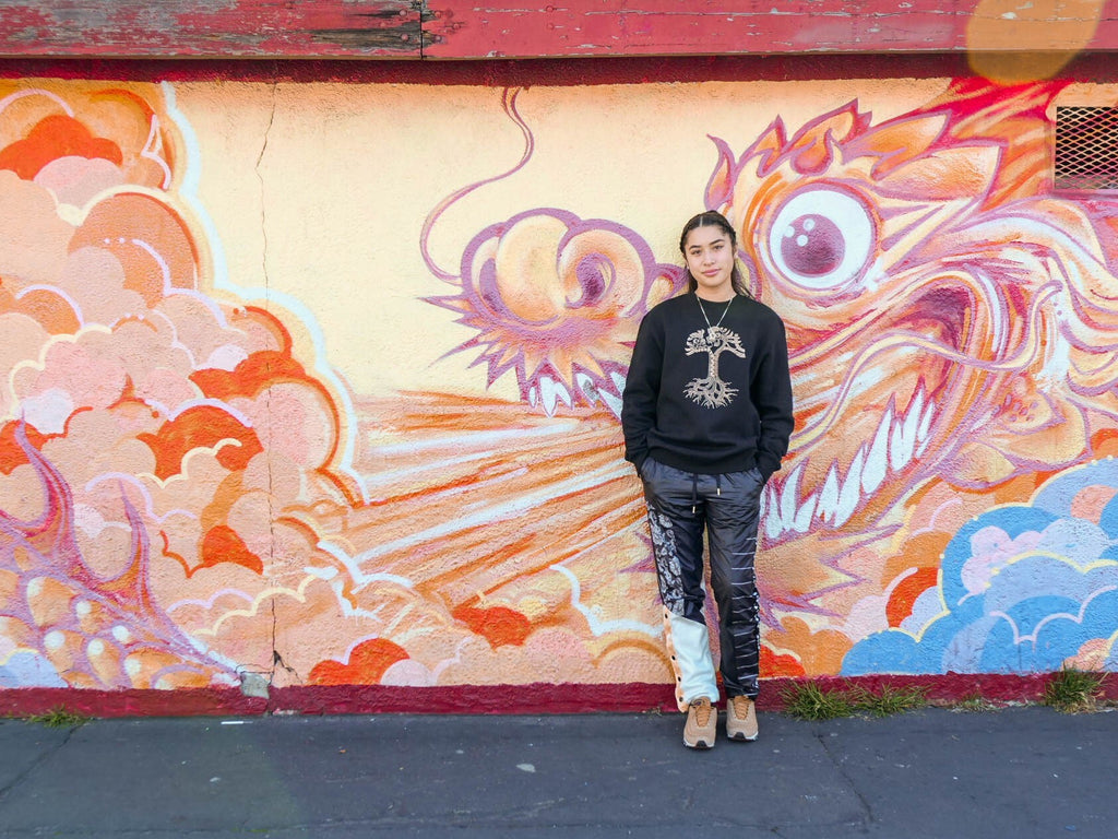 Female model wearing dragon power crewneck in front of dragon mural.