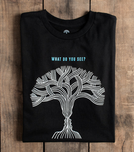 Black tee with text what do you see? and two faces or tree.