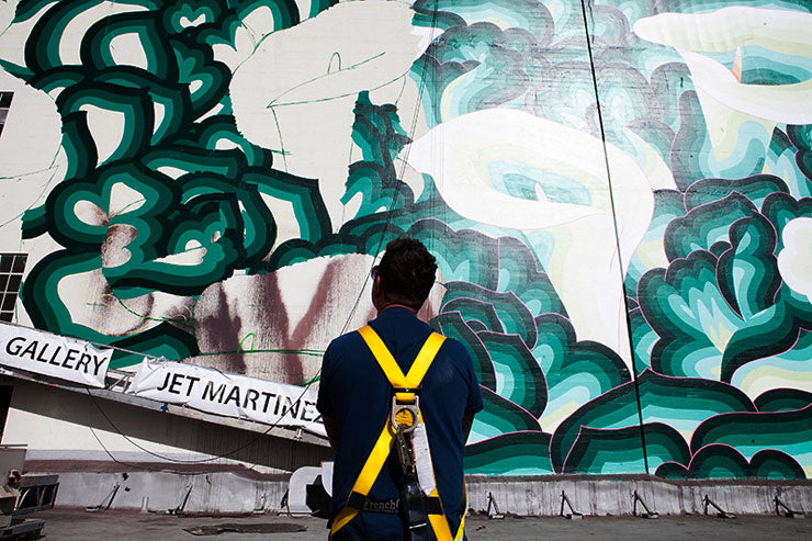 artist outside in front of work in progress on wall