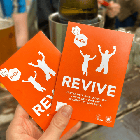 A person holding B On 1 Revive Patches with beer and wine in the background.