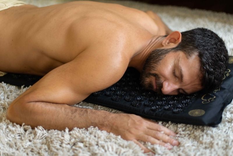 Man lying prone on black acupressure mat from ShaktiMat