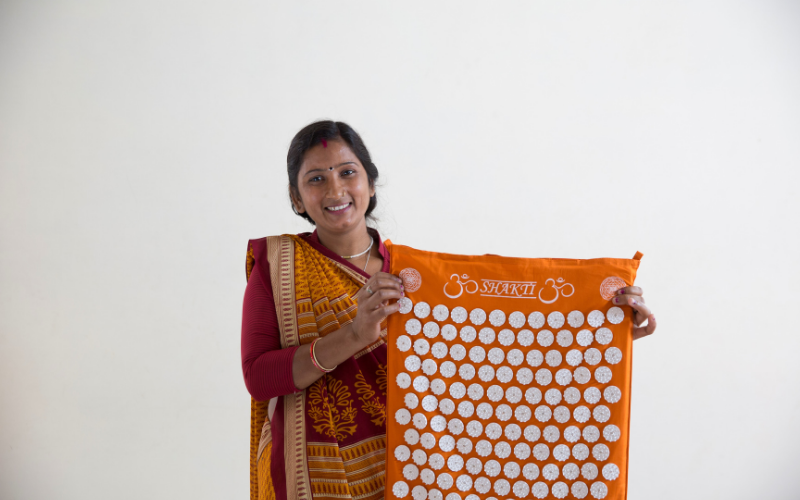 Female person in traditional sari holding acupuncture mat from ShaktiMat