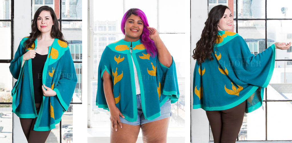 In the left and right photos, Devan (a fair skinned size medium model with long dark hair), and in the center photo, Jade (a dark skinned size 2X model with purple hair), model the Russian Princess Knit Cape. The knit circle cape with two arm holes has a dark teal body with light teal knit along the collar and hem, and features golden yellow designs along the front, back, and collar.