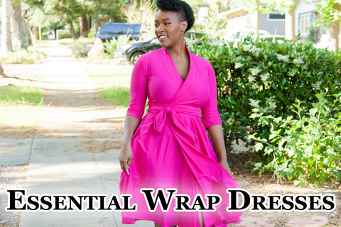 Essential Wrap Dresses - Lynsi (a dark skinned, dark haired model) is walking towards camera wearing a bright pink wrap dress with 3/4 sleeves. Green bushes and a sidewalk are in the background.