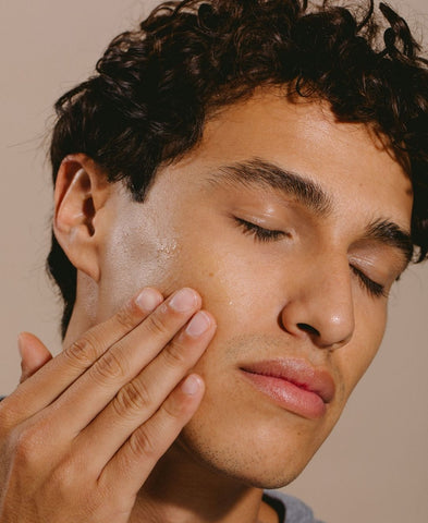 Close up of a man's face feeling his soft skin. 