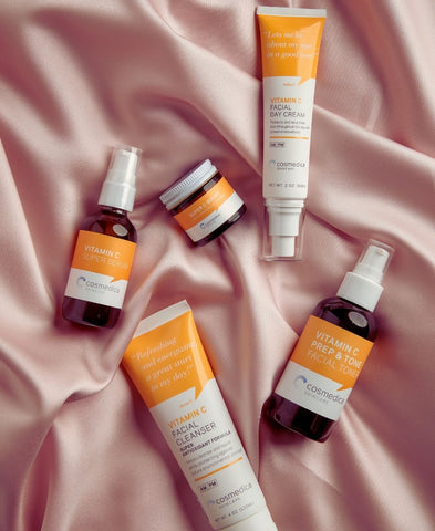 A variety of Cosmedica Skincare Vitamin C products lying on a silk cloth. 