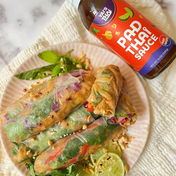 plate of spring rolls with bottle of yai's thai pad thai sauce