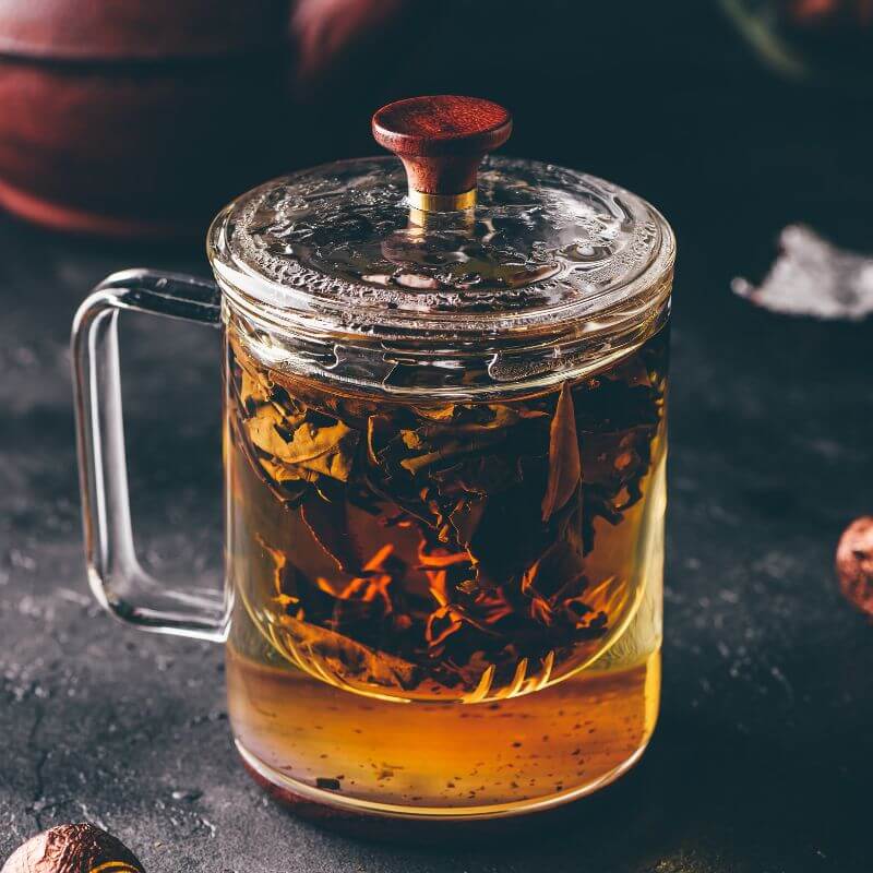 Loose leaf tea steeping in a clear tea pot.