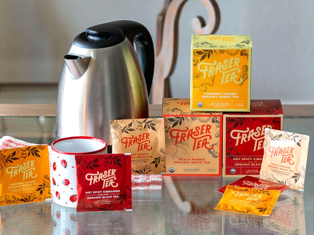 Tea kettle, tea cup and boxes of Fraser Tea on table. 