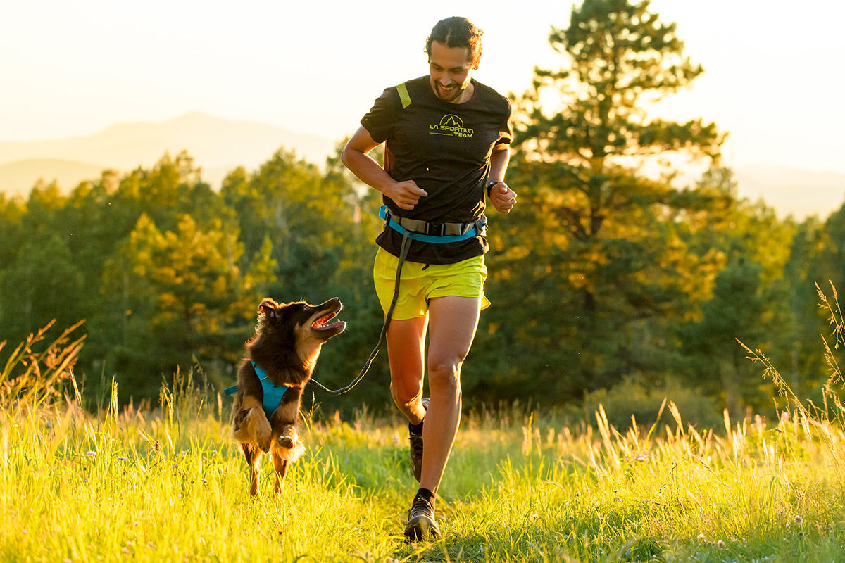 Sol runs alongside Nico looking up at him, clearly stoked about trail running.