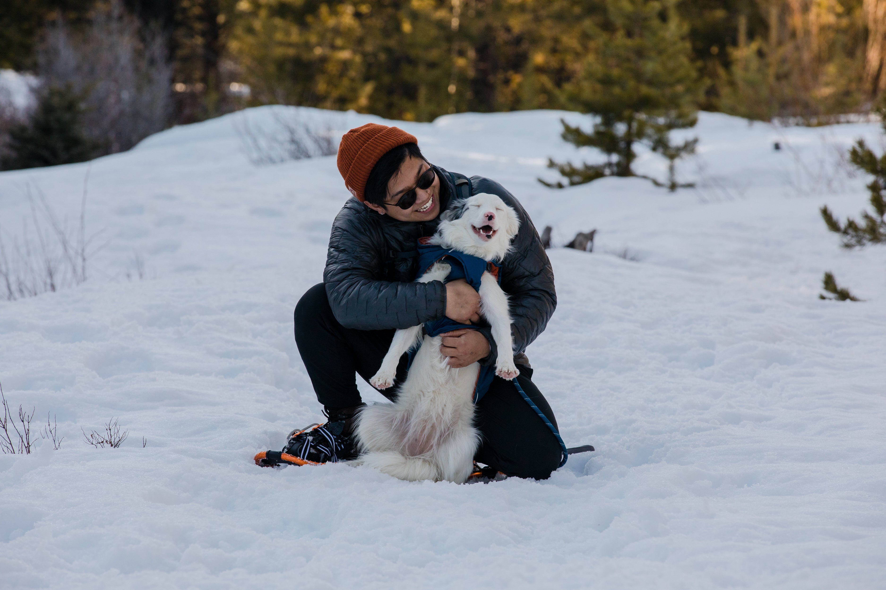 A man hugs his dog in the snow. 