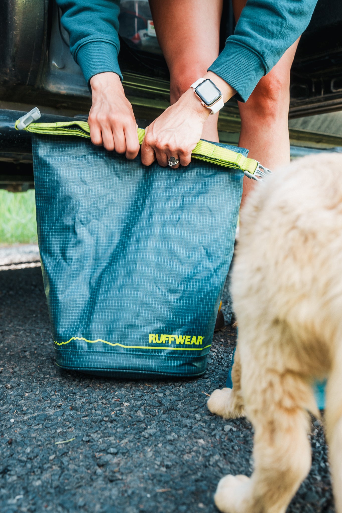A woman uses the Kibble Kaddie™ Dog Food Travel Bag while on a road trip. 