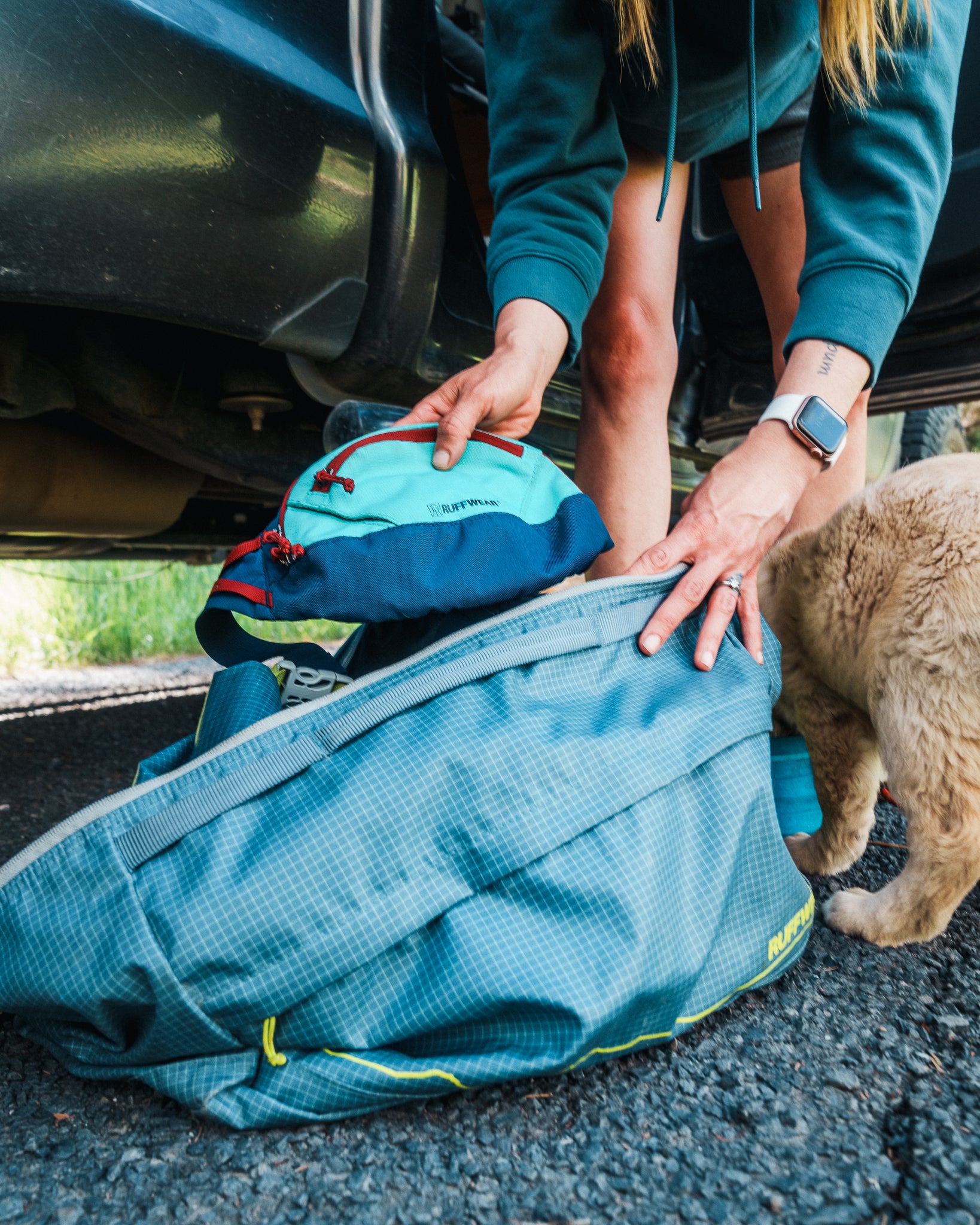 A woman opens her Ruffwear Haul Bag™ during a road trip. 