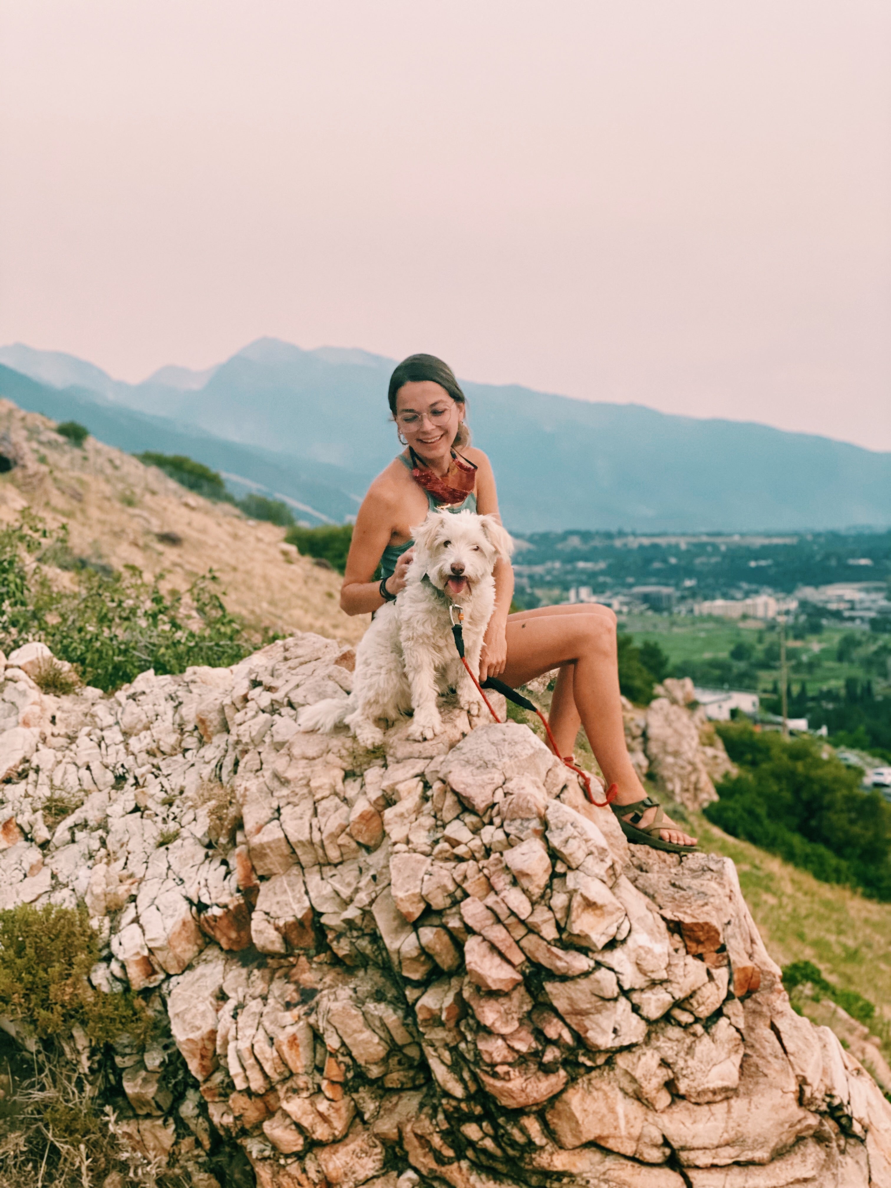 Woman and dog sitting on desert rocks