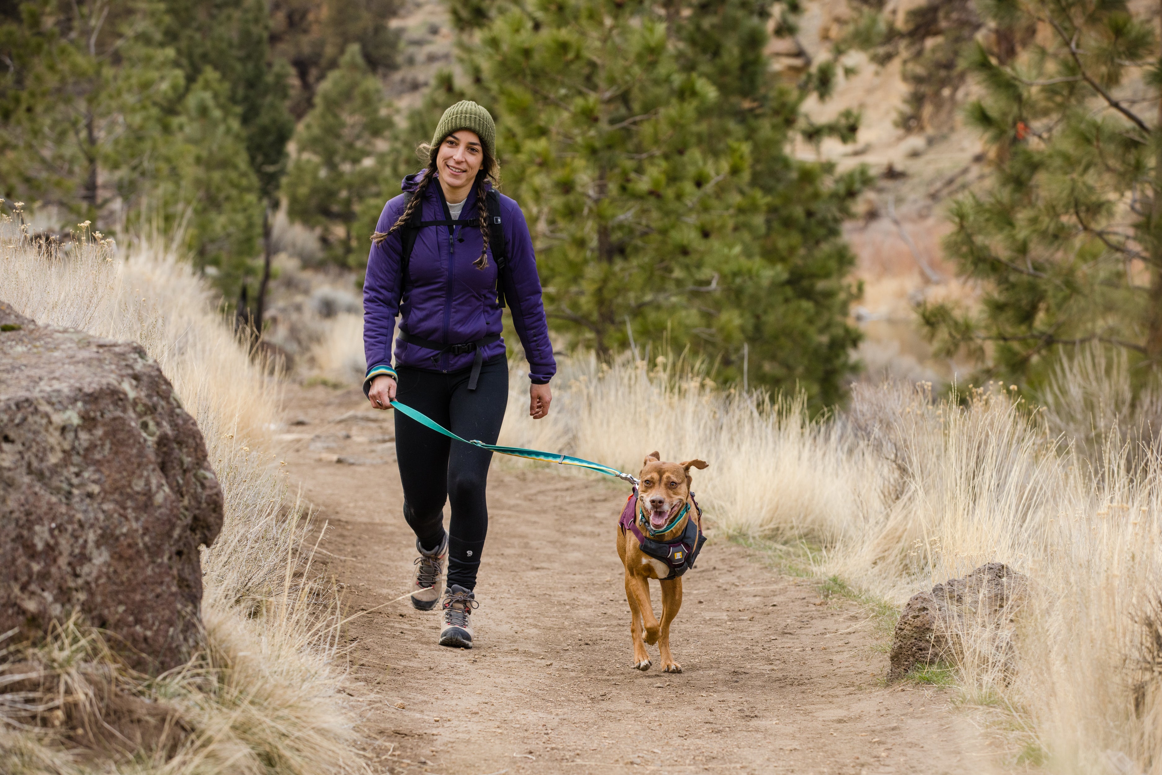 A woman and her dog walk on a hiking trail using the Crag™ Reflective Dog Leash.