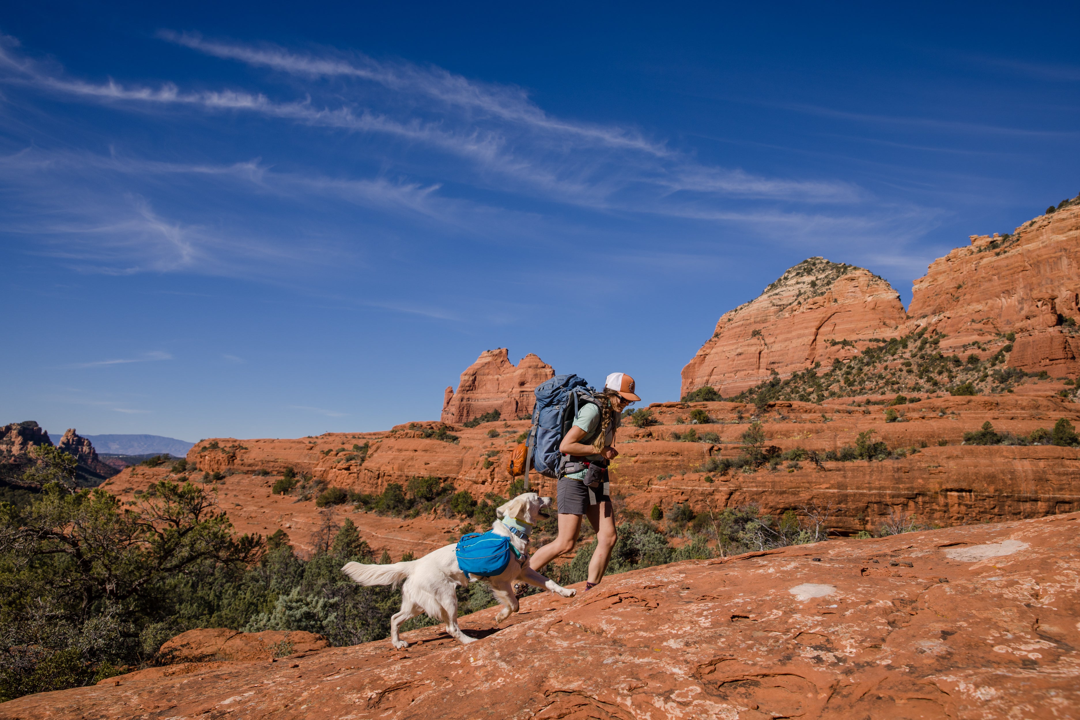 A woman hikes in Arizona with her dog, who is wearing Ruffwear's Approach Pack. 