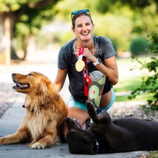 Allysa Seely poses with her two service dogs while holding a gold medal. 