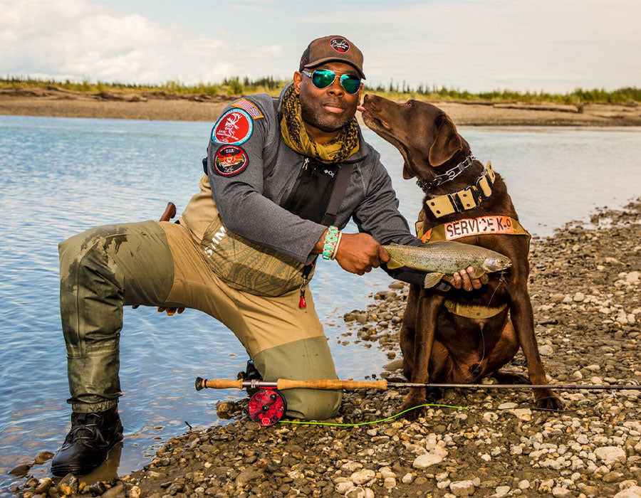 Chad and Axe show off their most recent fishing catch next to a river.