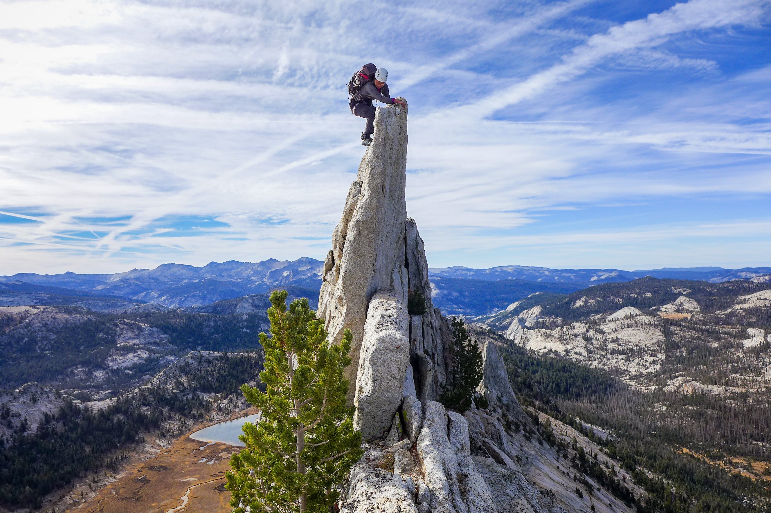 Anna rock climbing on top of a very narrow rock formation peak.