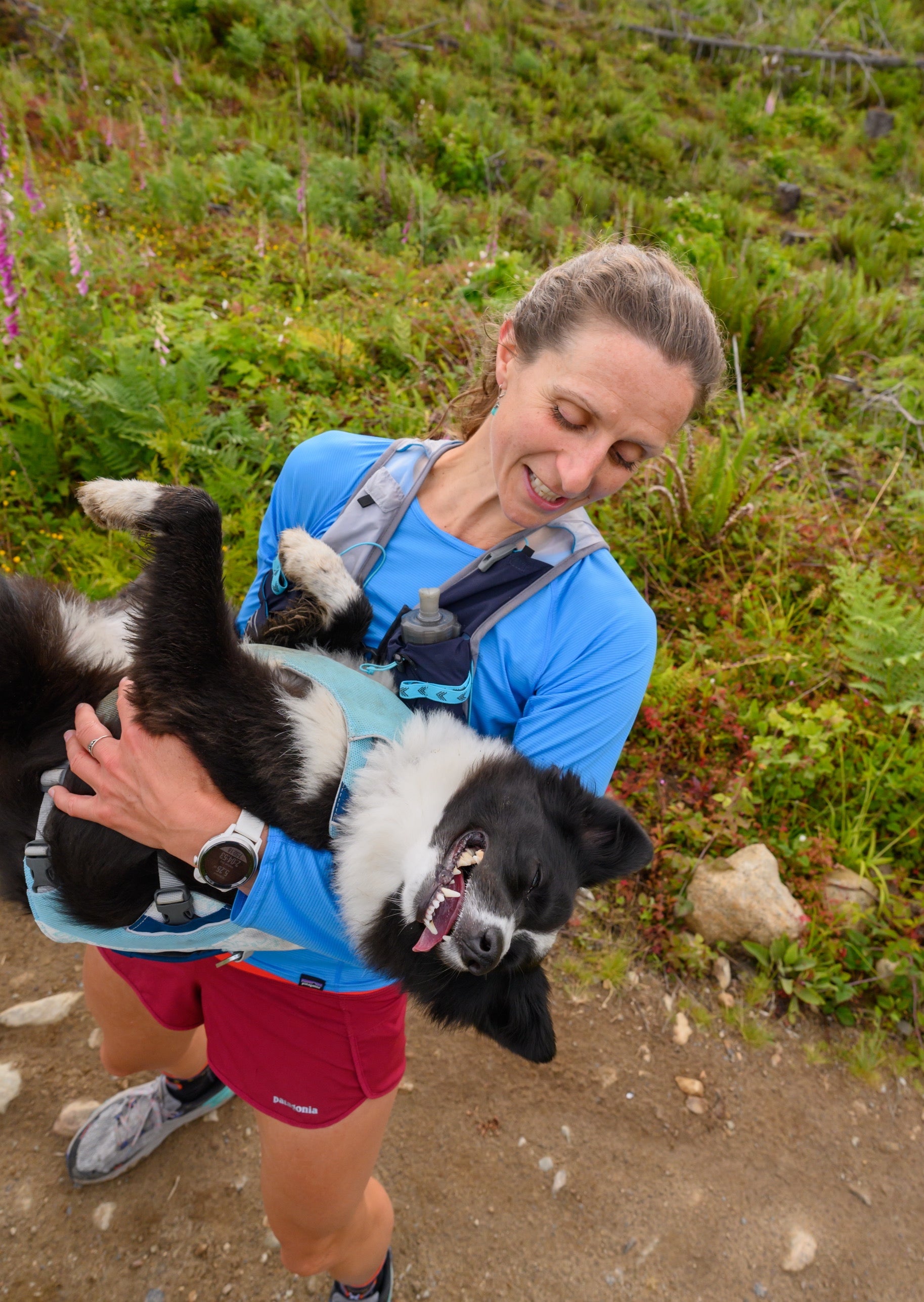 A woman holds her dog who is wearing a Ruffwear Swamp Cooler Vest. 