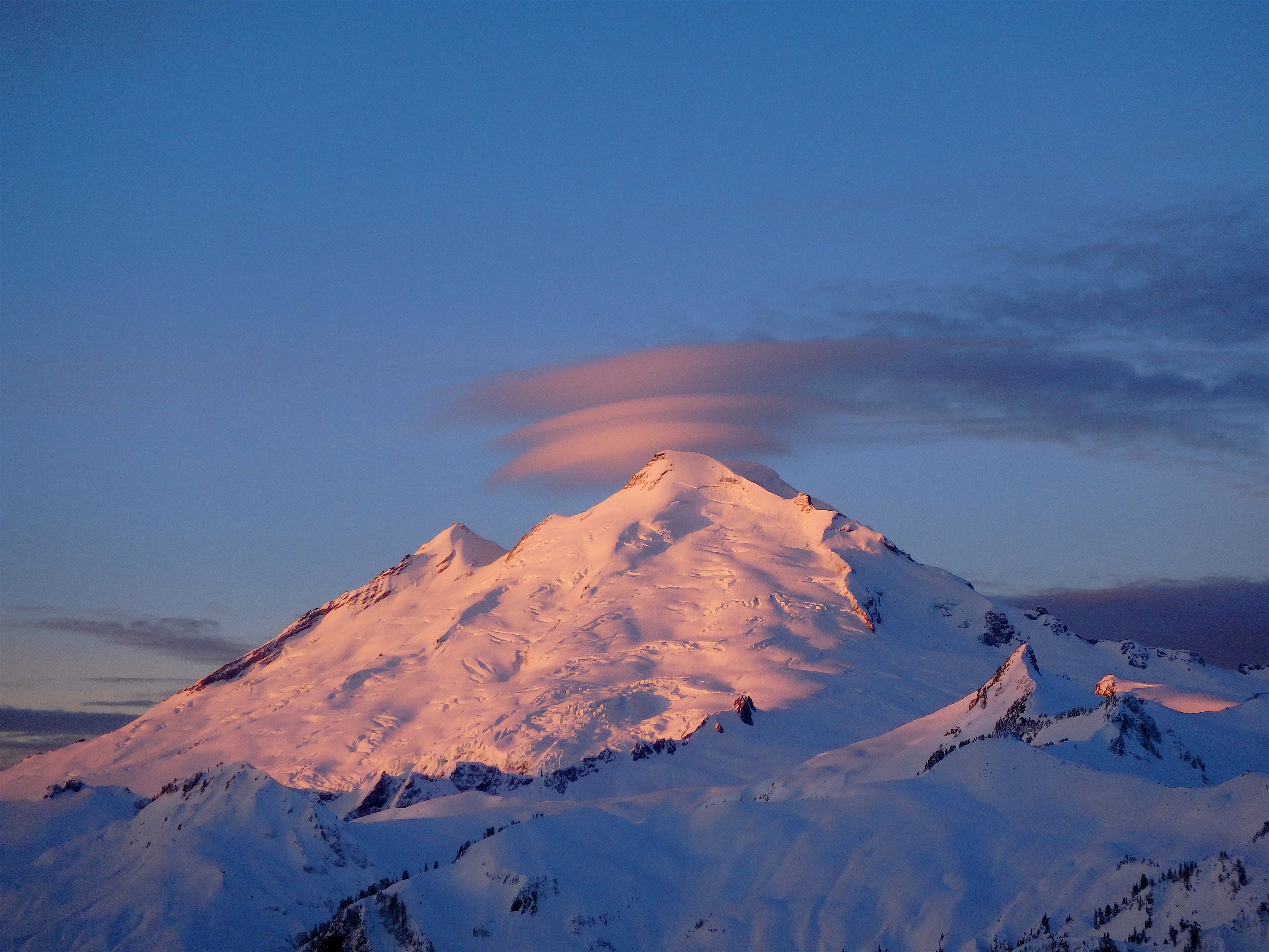 The sun rises over a snow-covered mountain. 