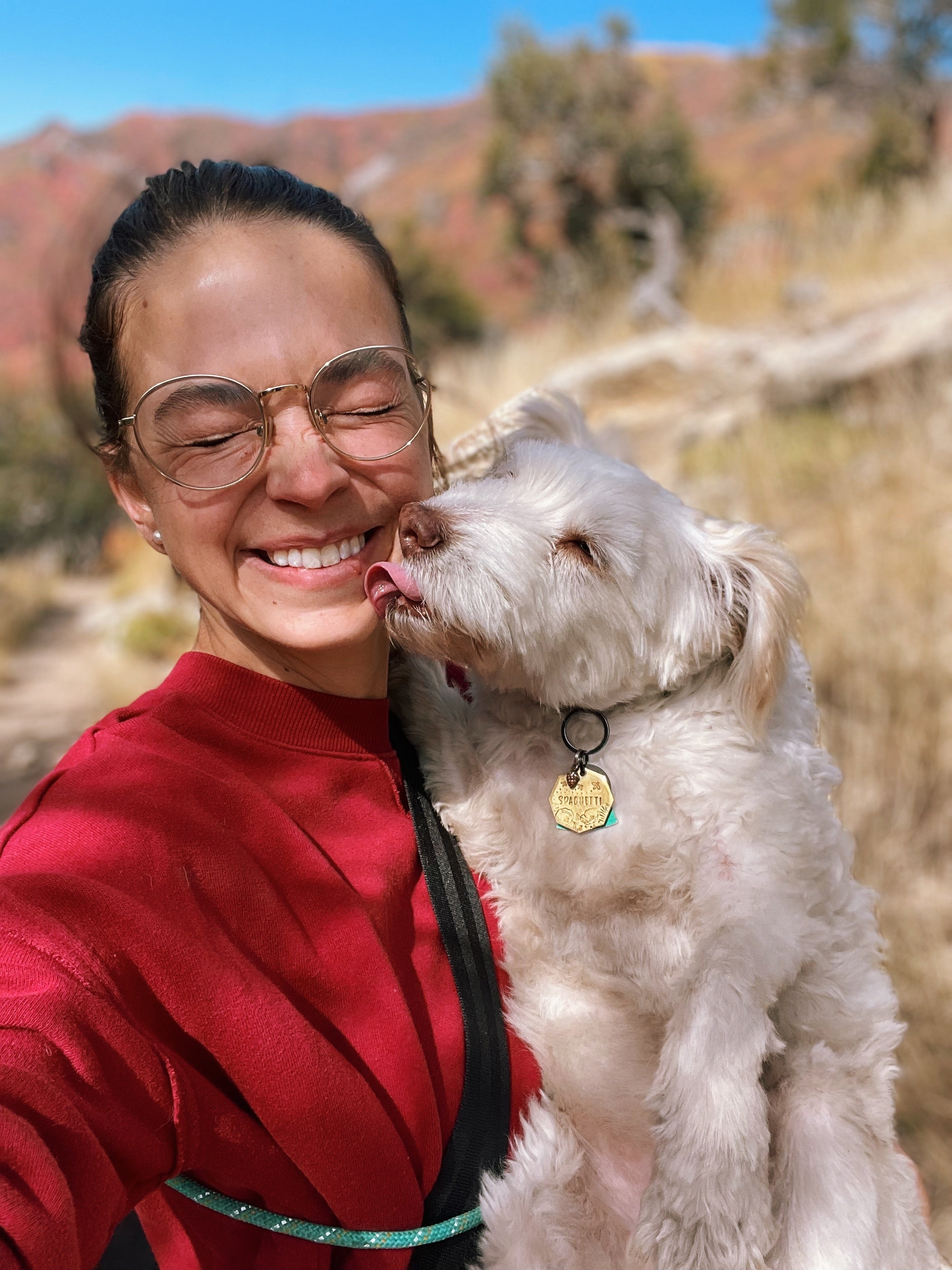A woman holds her dog who licks her on the face. 