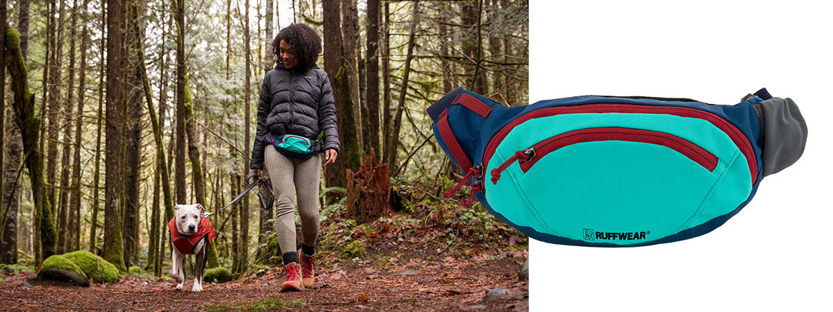 Alexis wears home trail hip pack and walks dog Cookie, wearing a overcoat, through Forest Park.