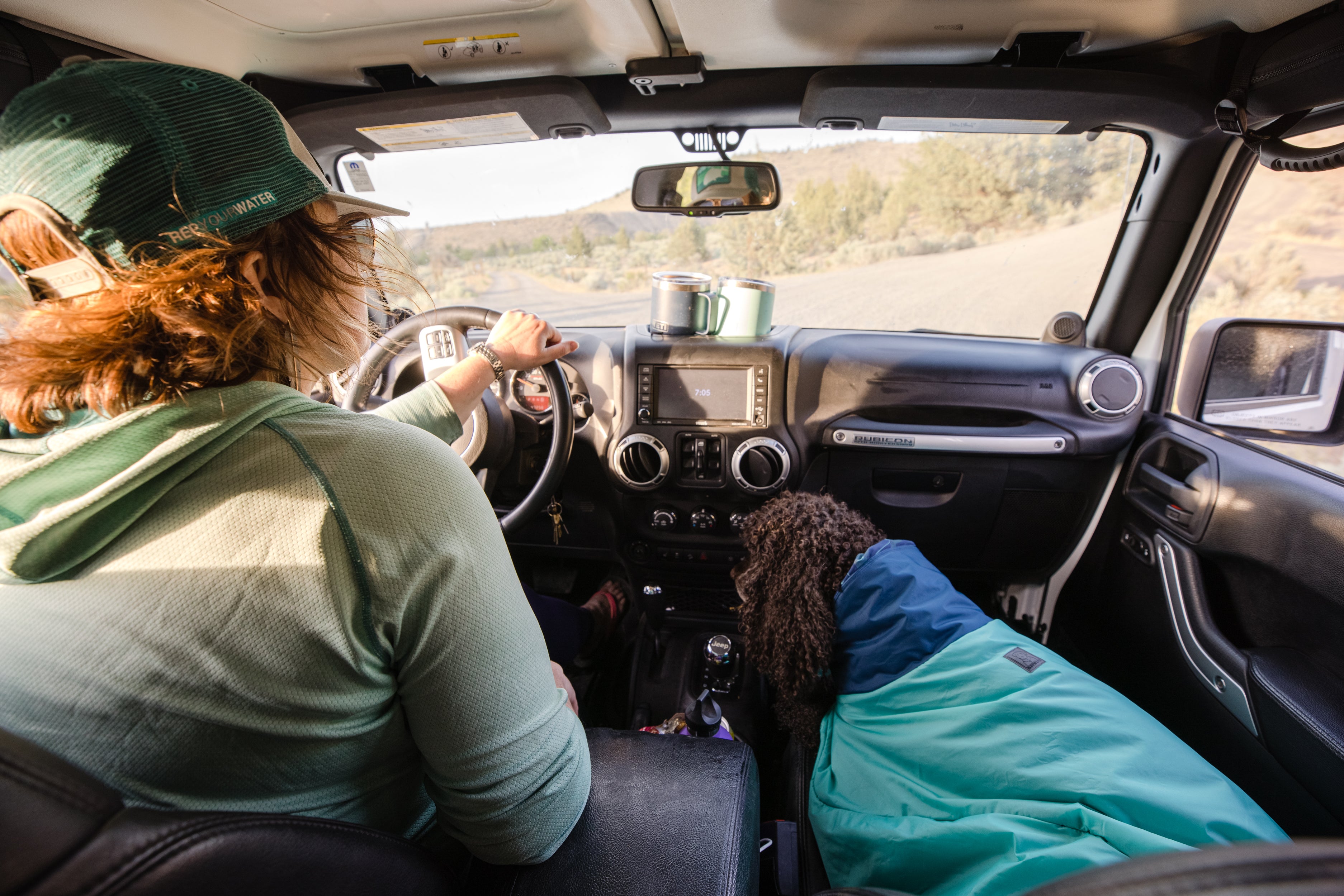 Dog in dirtbag towel in front seat of car next to Dove driving.