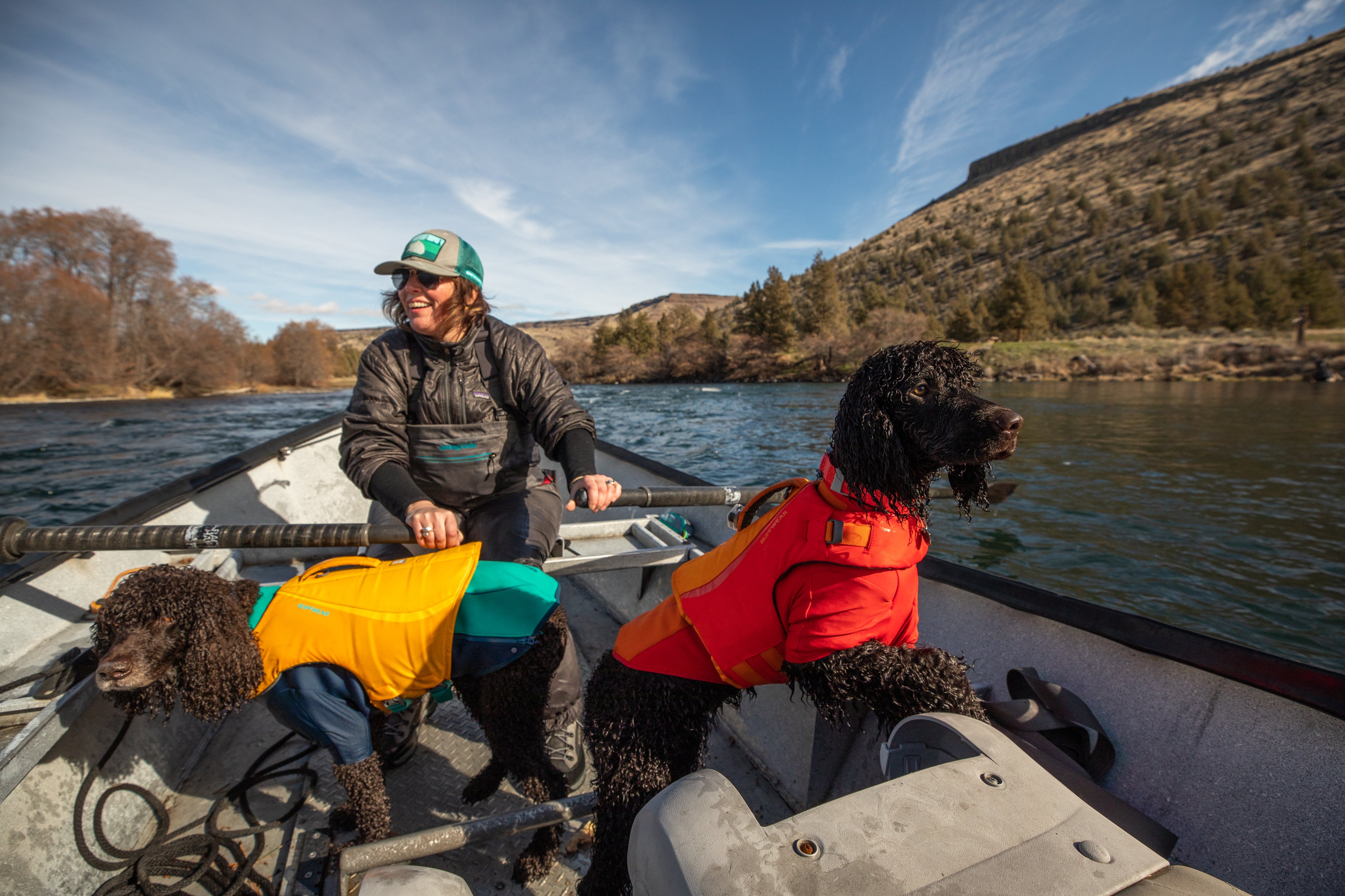 Dove rows fishing boat down Deschutes River with dogs Midge and River in Float Coats and Undercoats.