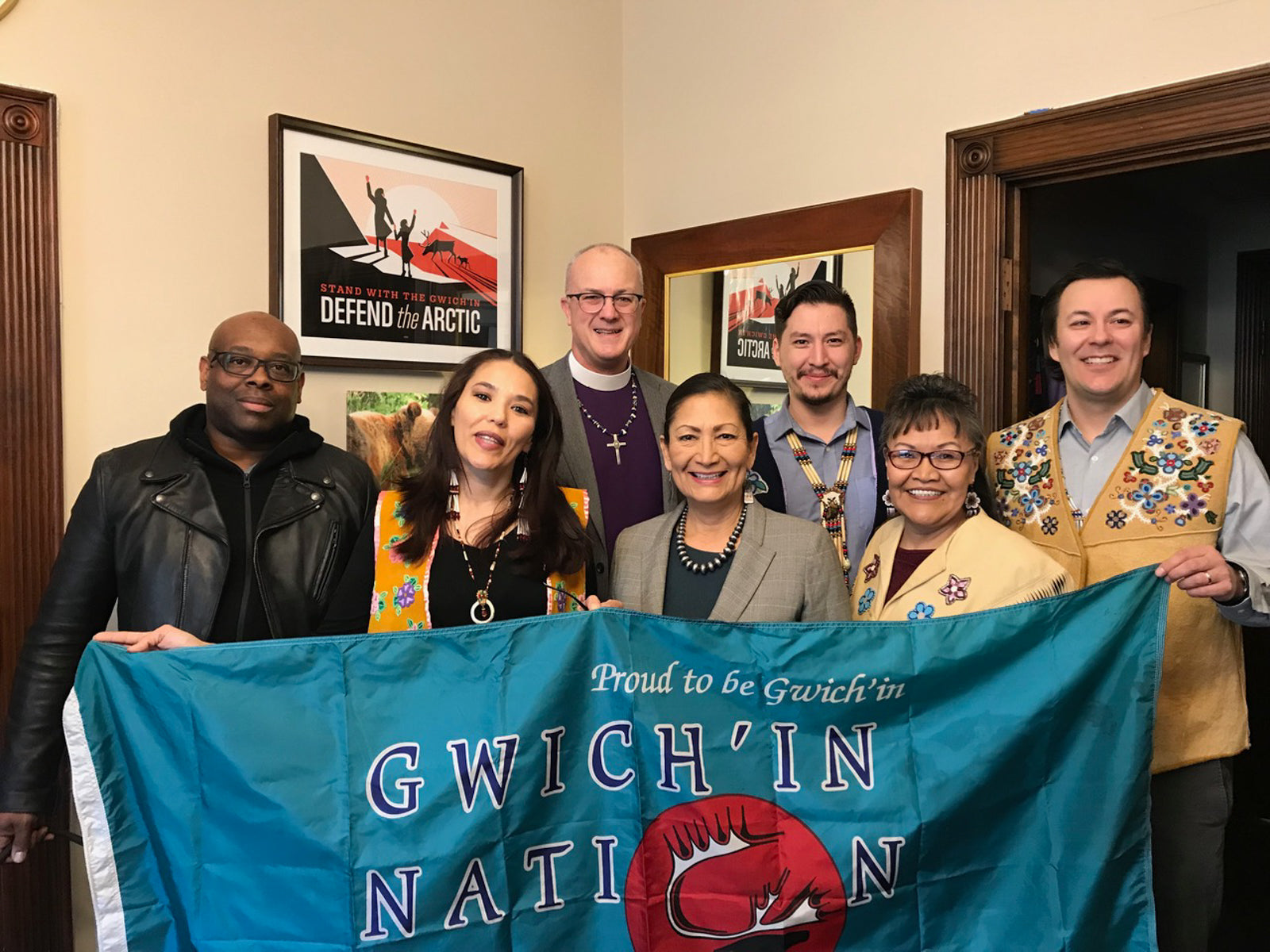 Group of individuals in Congressional offices hold a flag that reads "proud to be gwich'in nation"