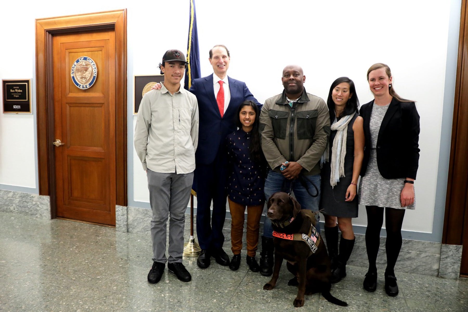 Chad and Axe and group of individuals take a photo with congressperson at Oregon state capital.