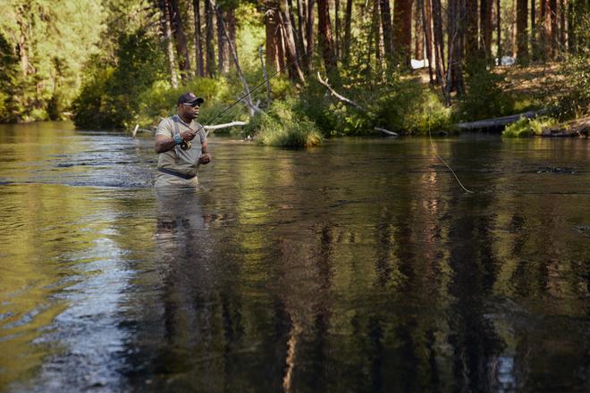 Chad stands fly fishing in the middle of the river.