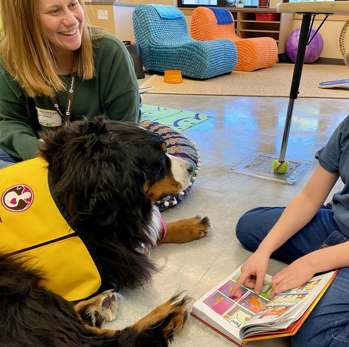 Dog sitting next to child with book.