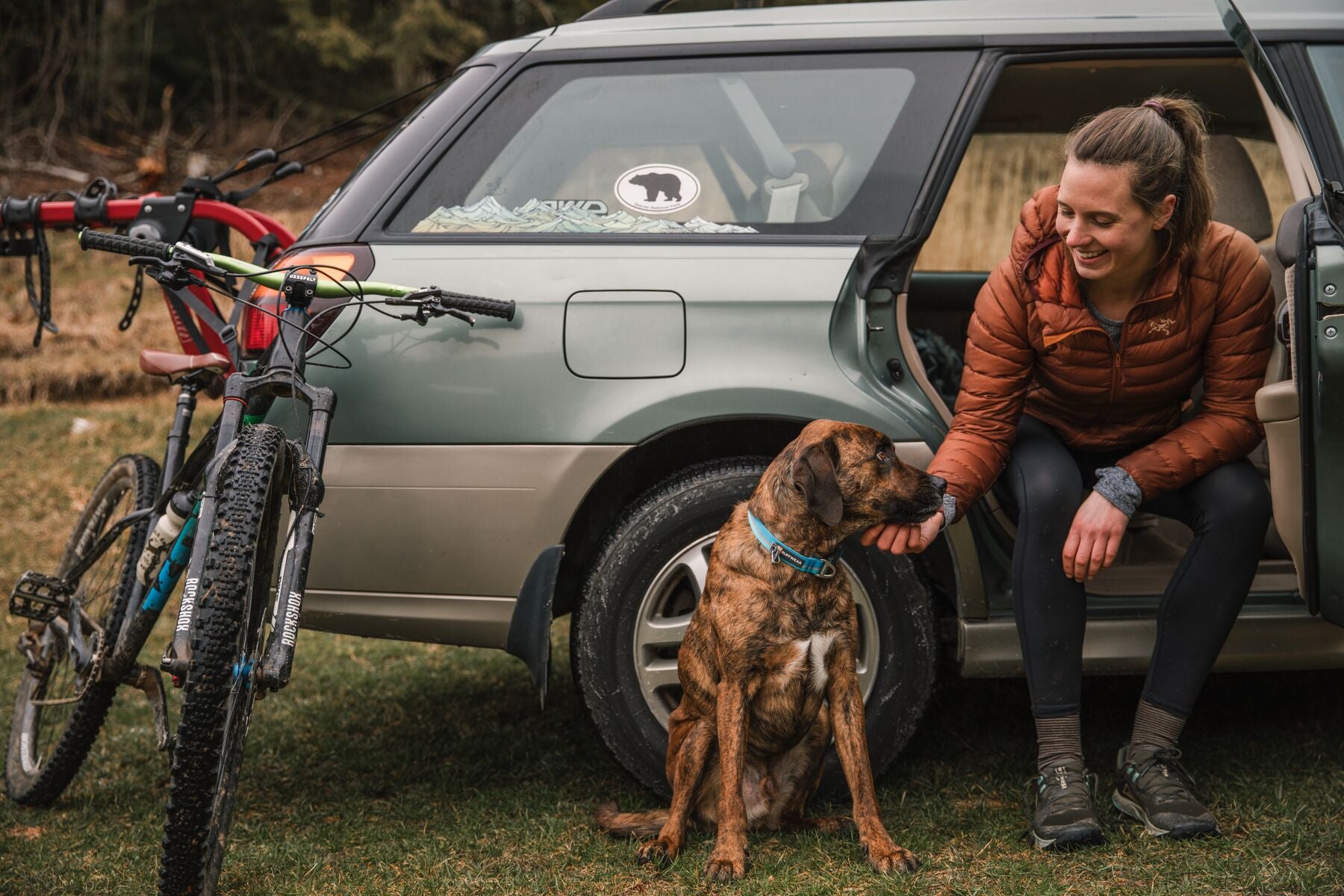 Woman petting dog at the car after mountain bike ride.