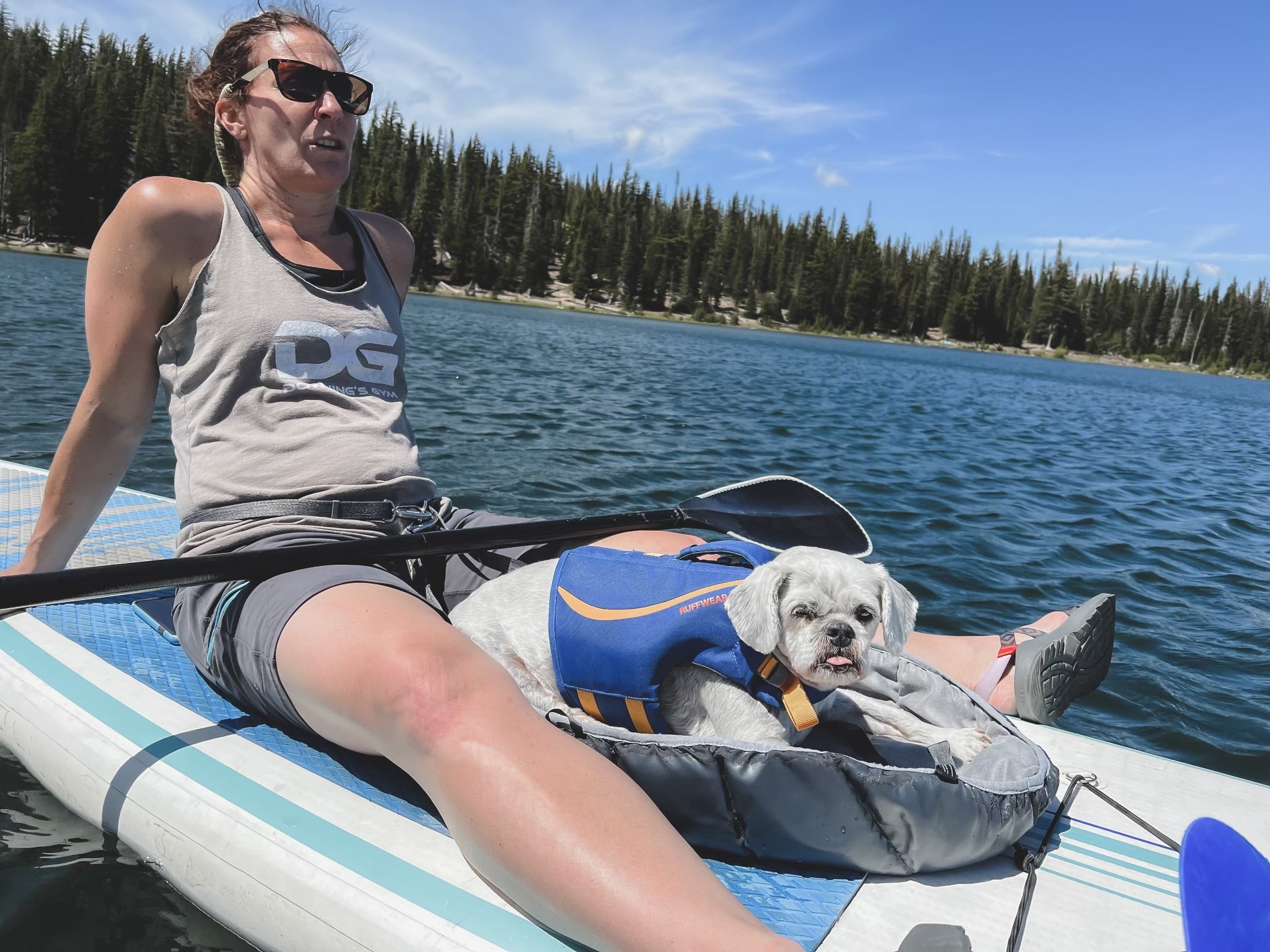 Woman sitting on paddleboard with small dog