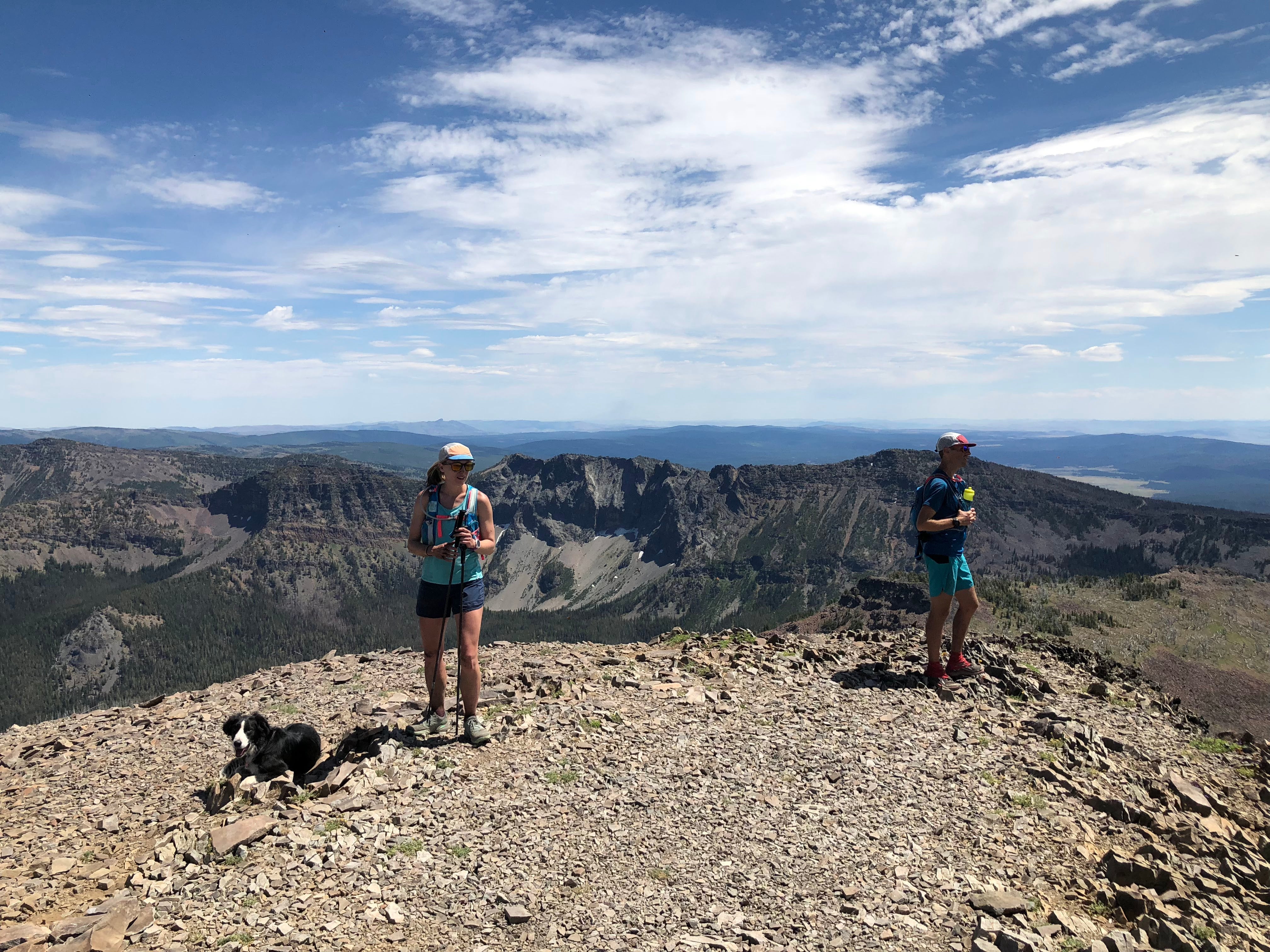 Dog and two humans high up on a mountain top in the wilderness