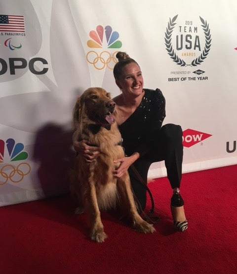 Allysa Seely poses at a Paralympics event with her golden retriever service dog. 