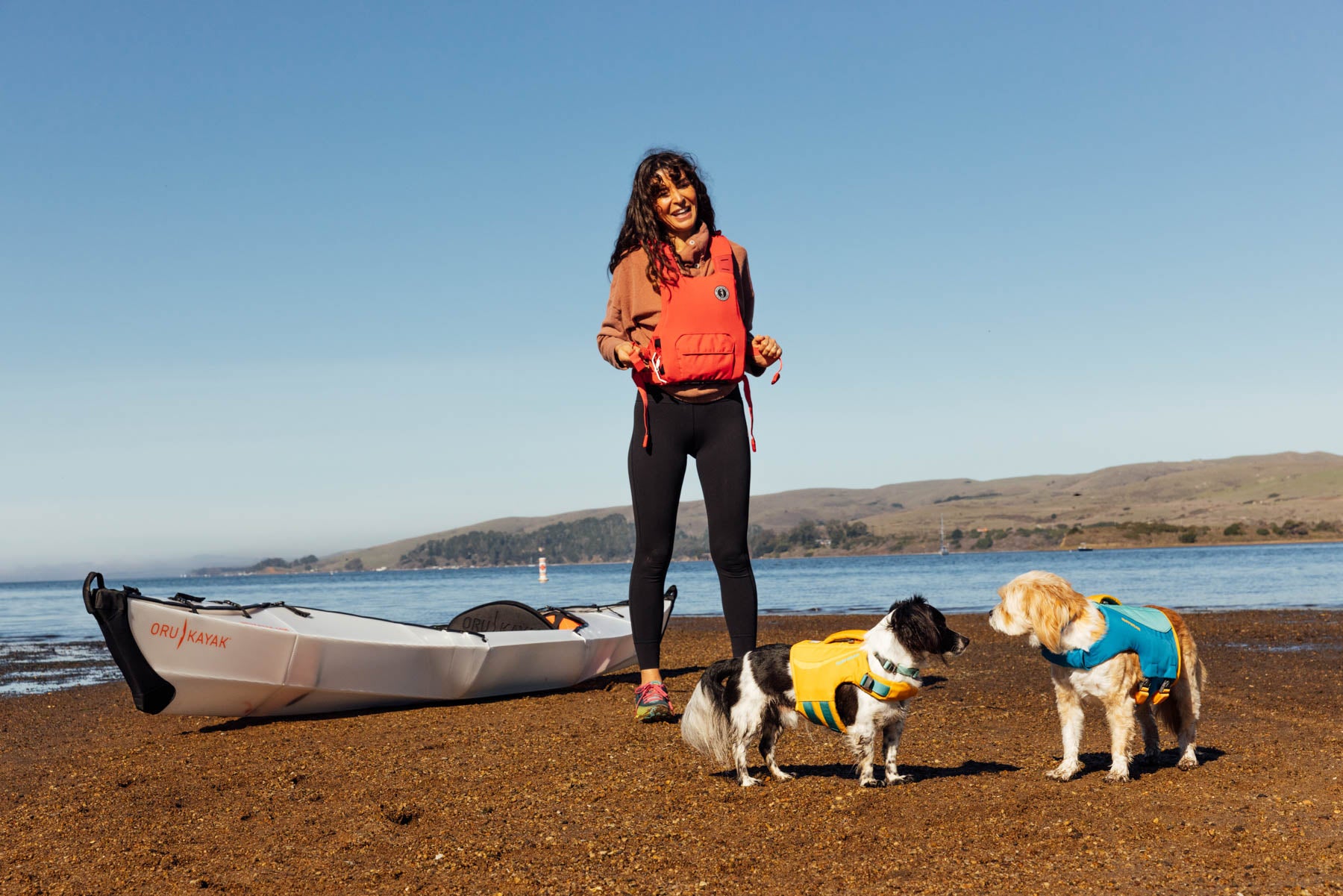 Noel Russel and her dogs, Sue and Fin on a lakeshore with a kayak