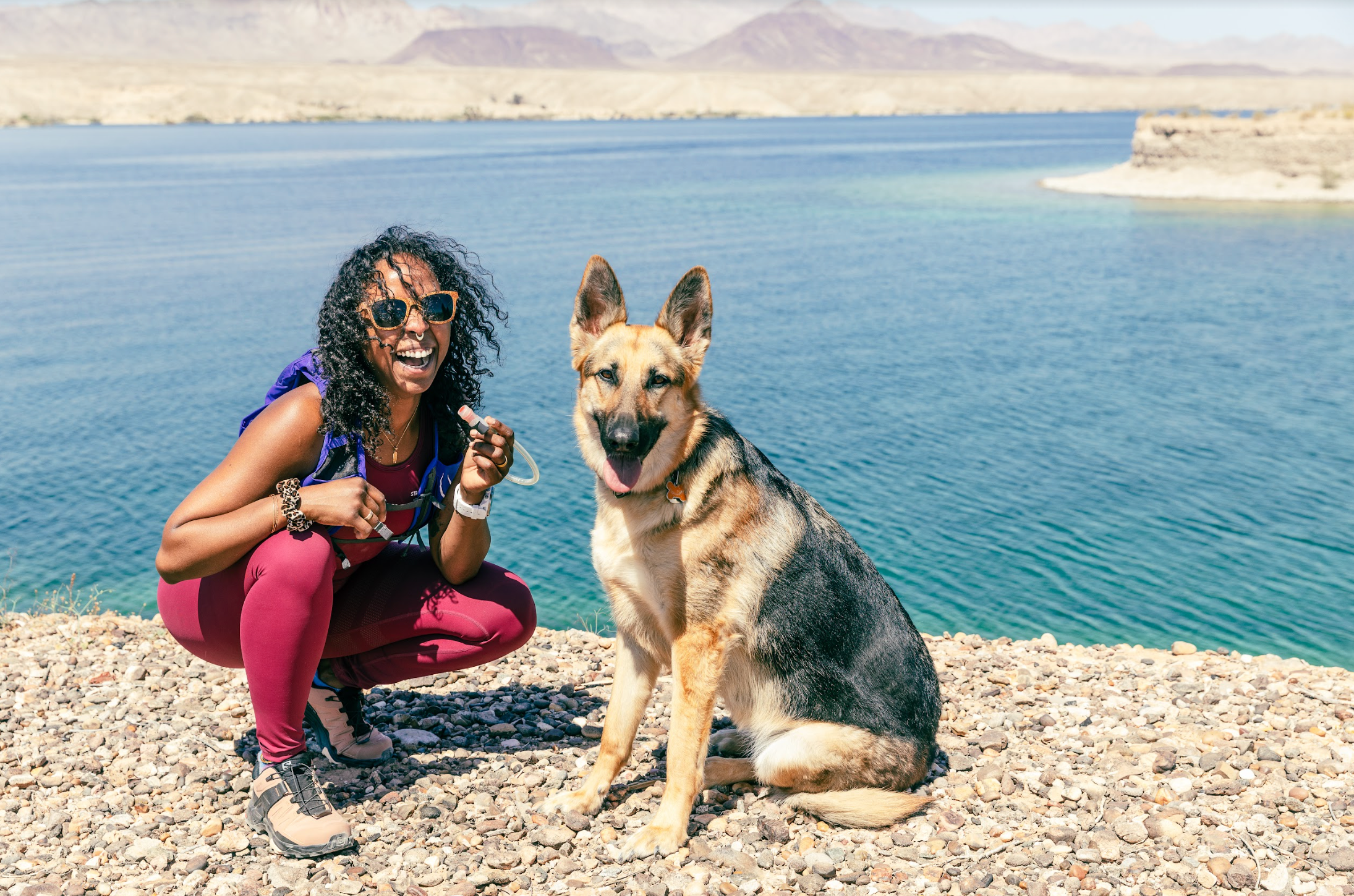 Woman and dog taking a break from a run in front of a lake.