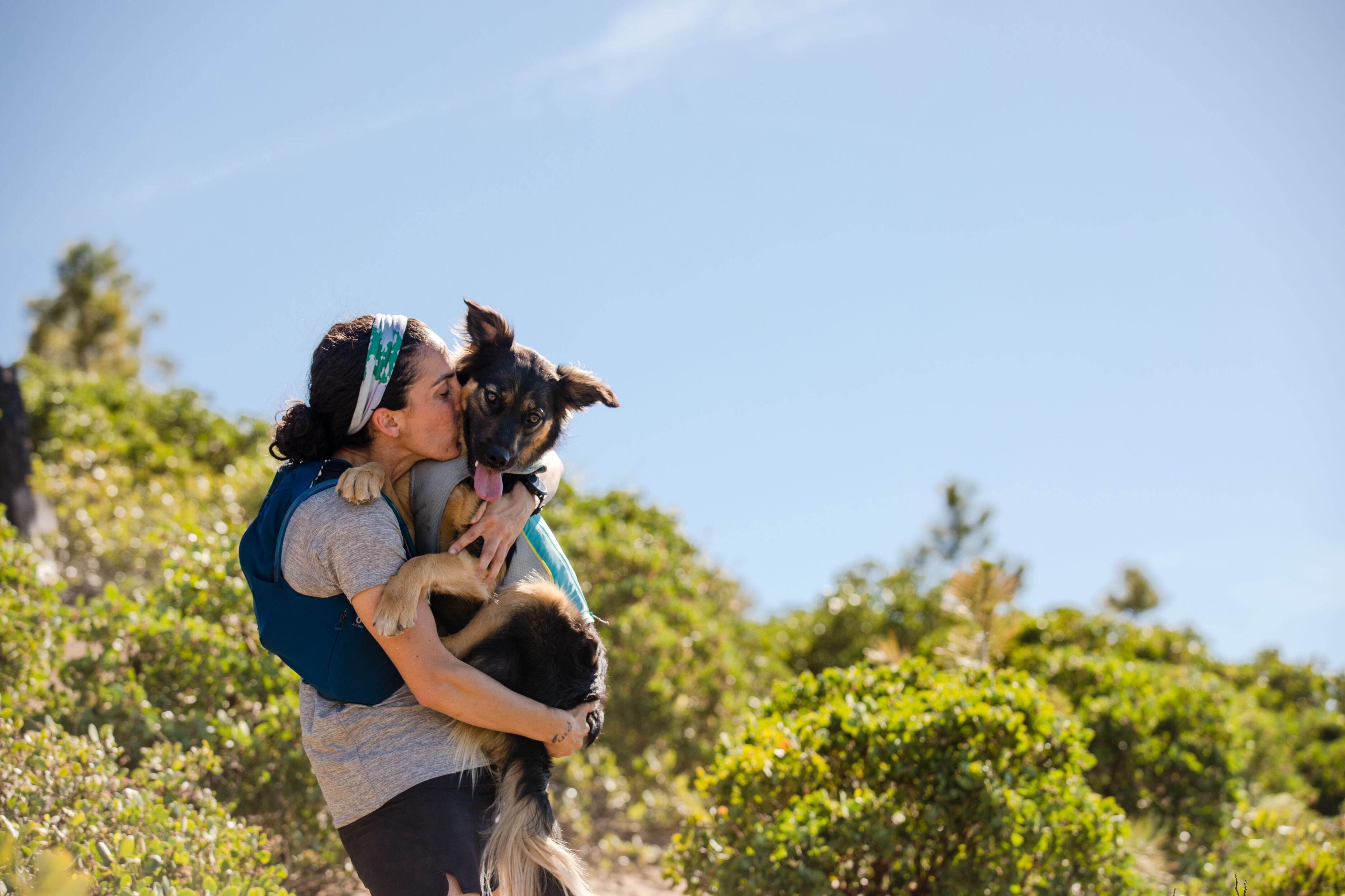 Cristina gives dog Lennon - wearing a jet stream dog cooling vest - a kiss while on a trail run.