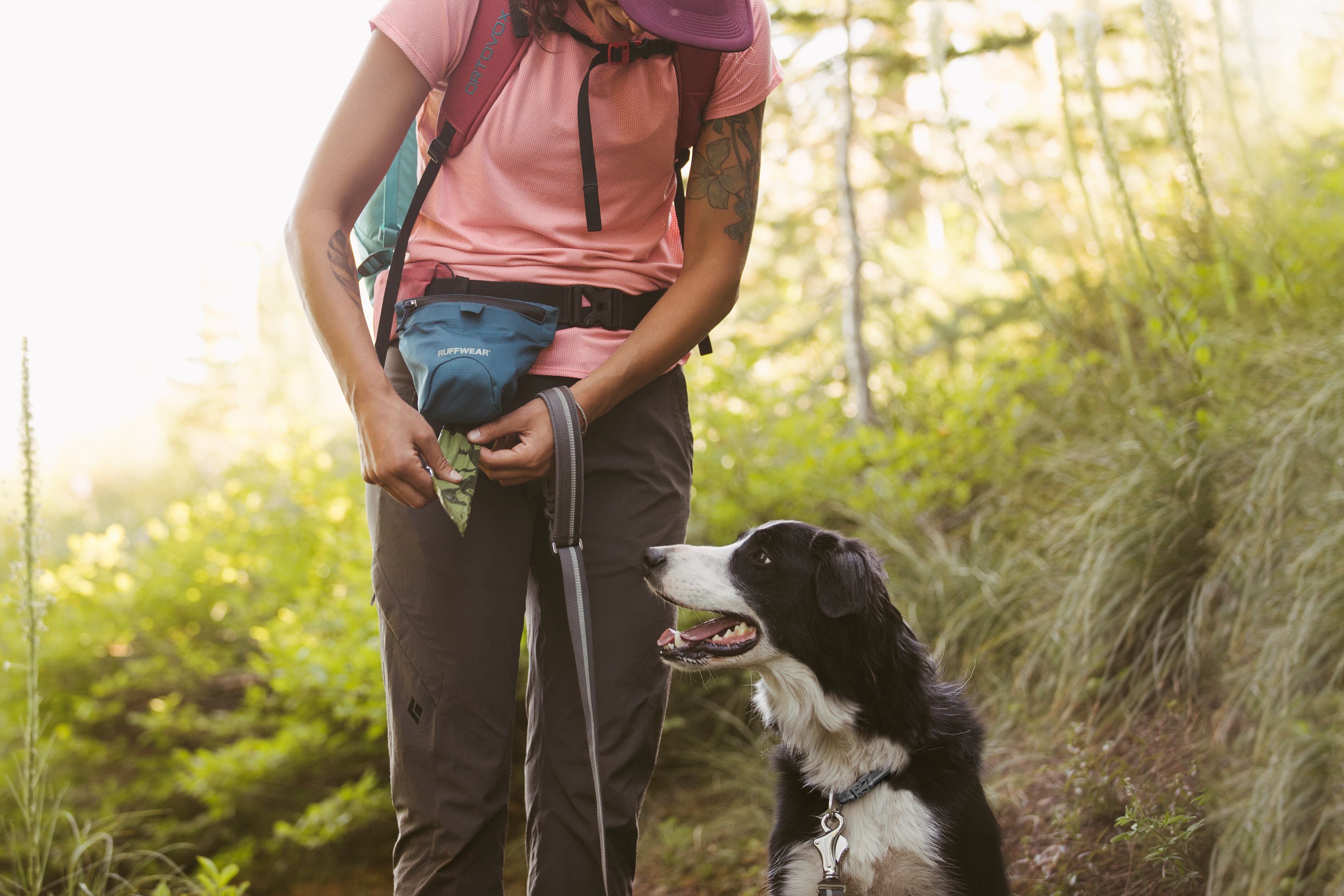 A woman pulls a pick-up bag out of the Ruffwear Pack Out Bag™. 