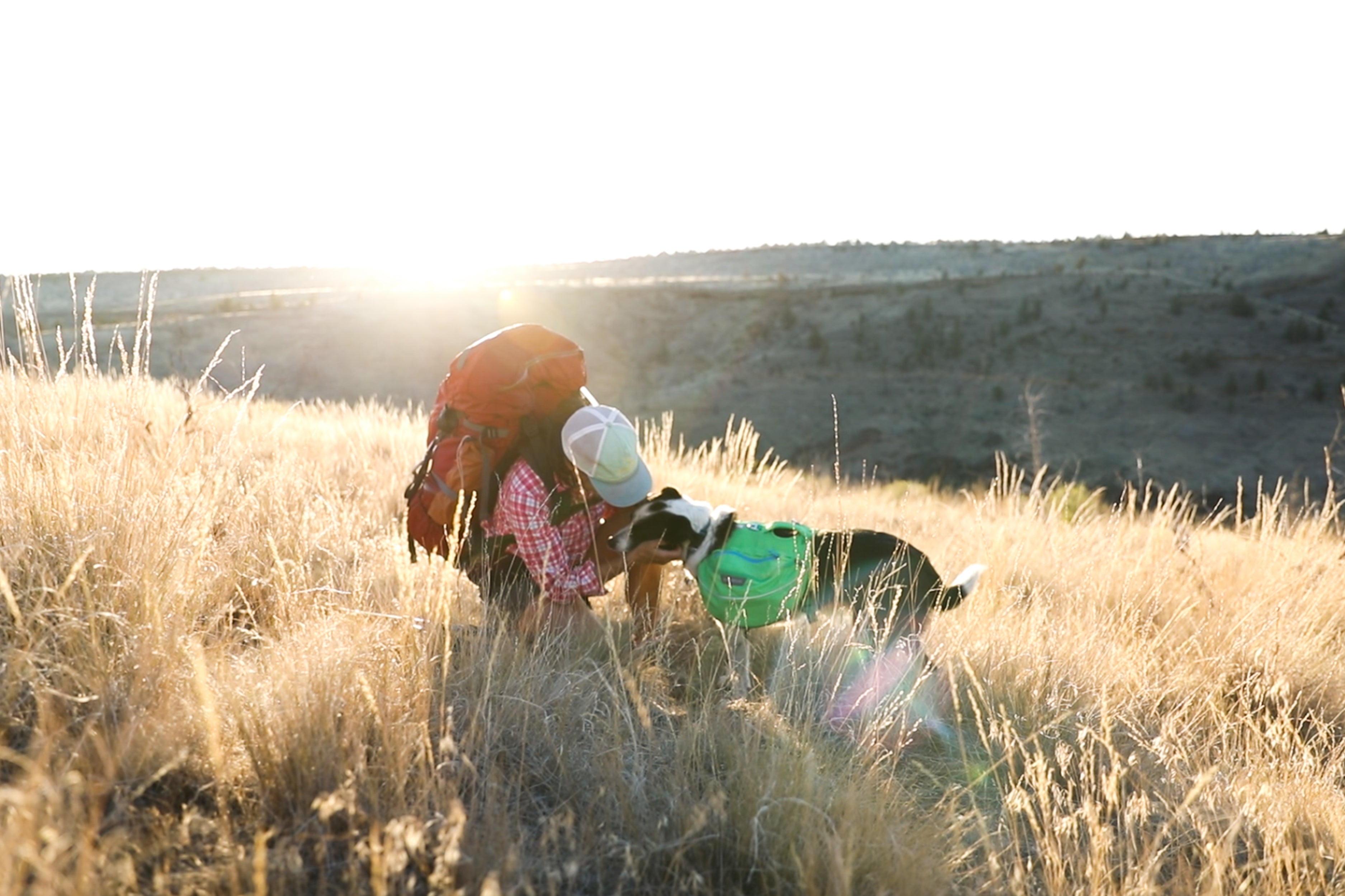 Elissa bends down to give dog Lula in Approach pack a kiss while backpacking.