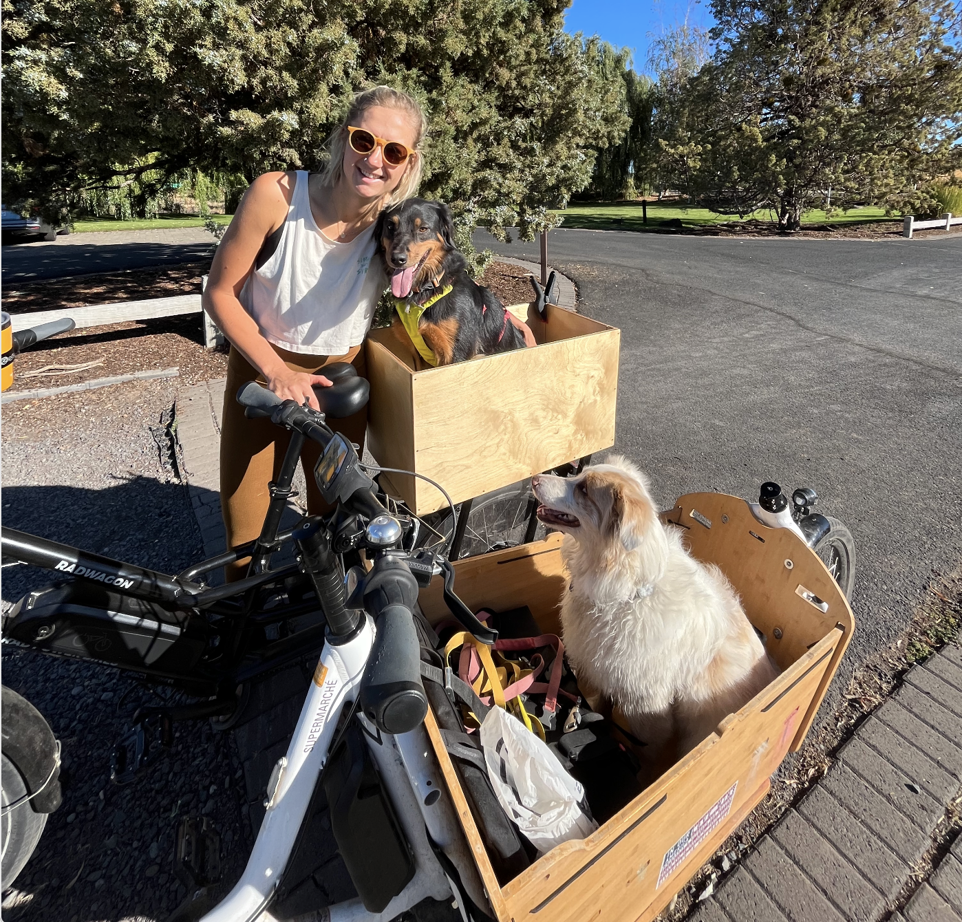 Woman standing next to dog in a bike cargo box - both happy