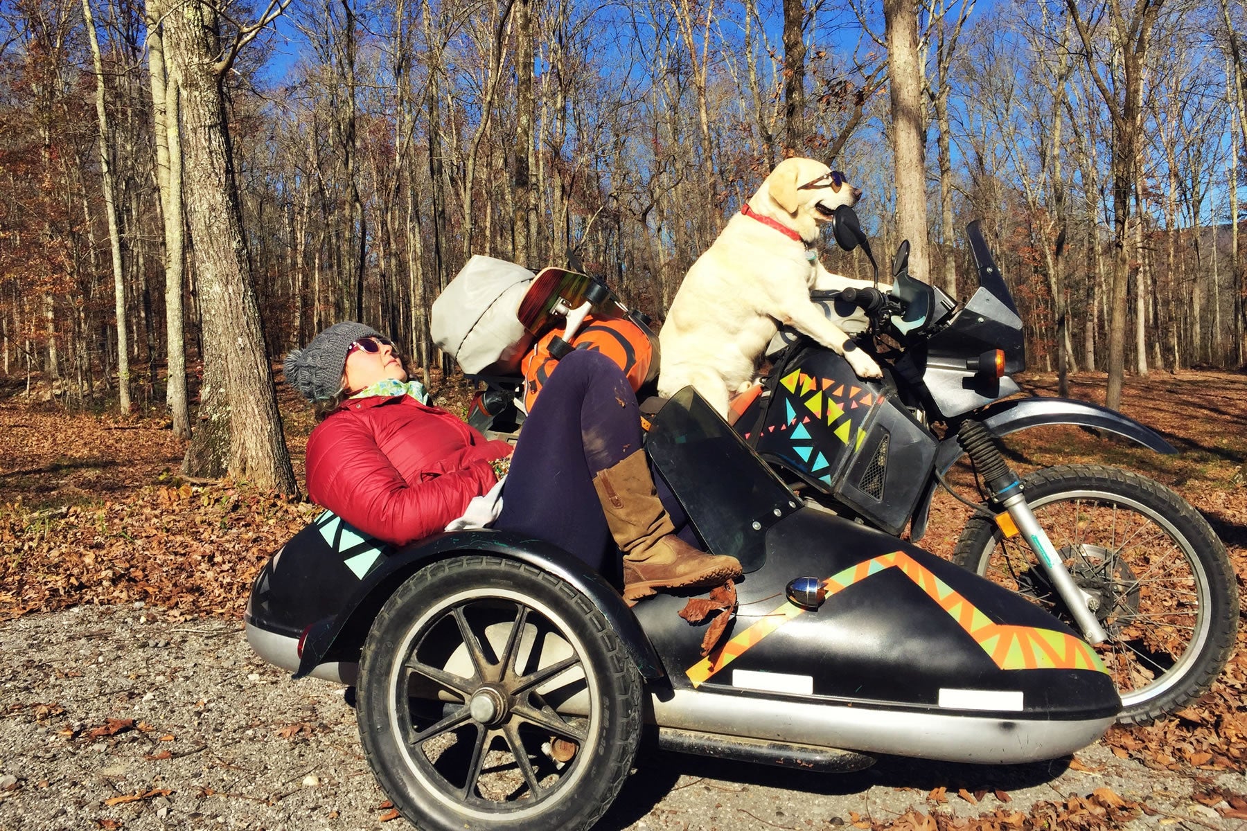 Baylor sits in the drivers seat of the motorcycle with sunglasses on while Mallory sits in the sidecar.