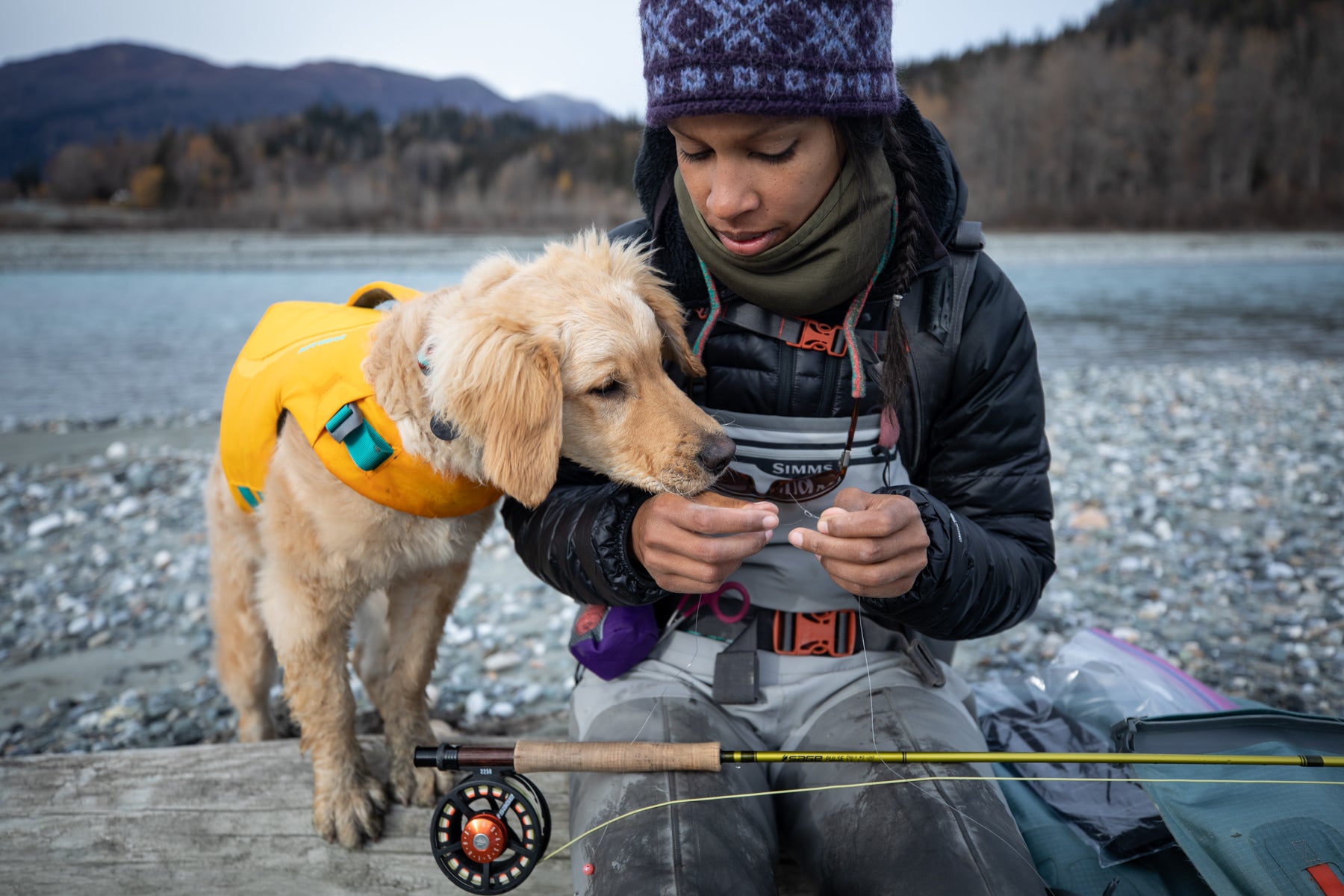 Sammy sniffs the fly that Chris is tying next to the river.