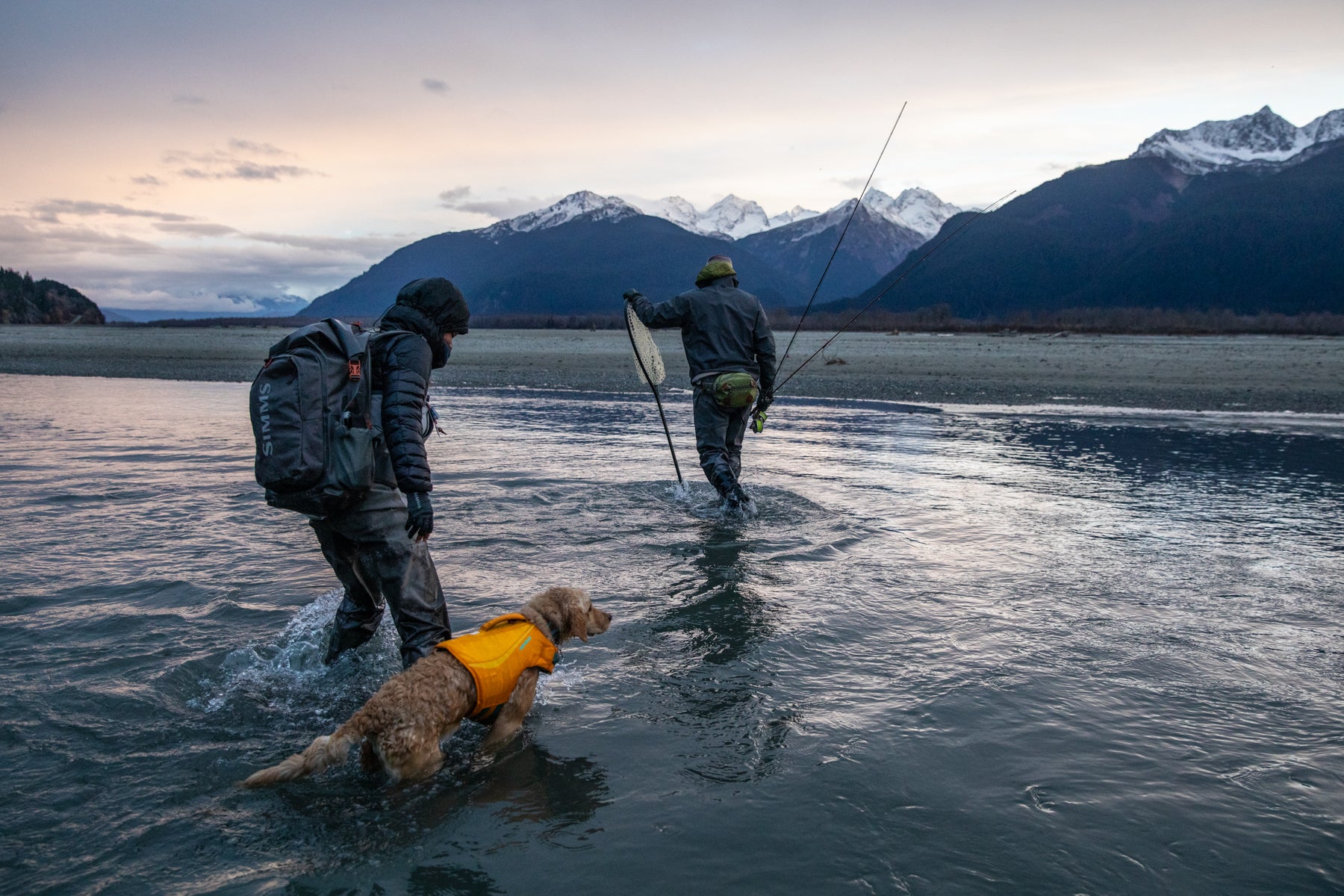 Chris, Greg and Sammy wade with fishing gear into the river.