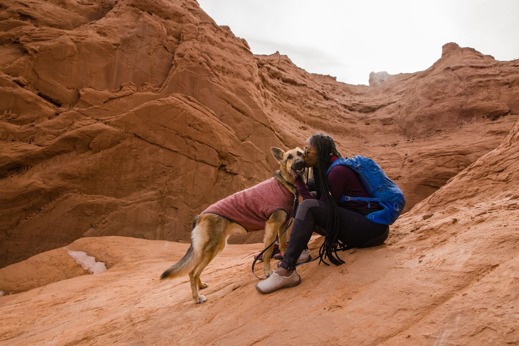 A woman gives her German Shepherd dog a kiss. 