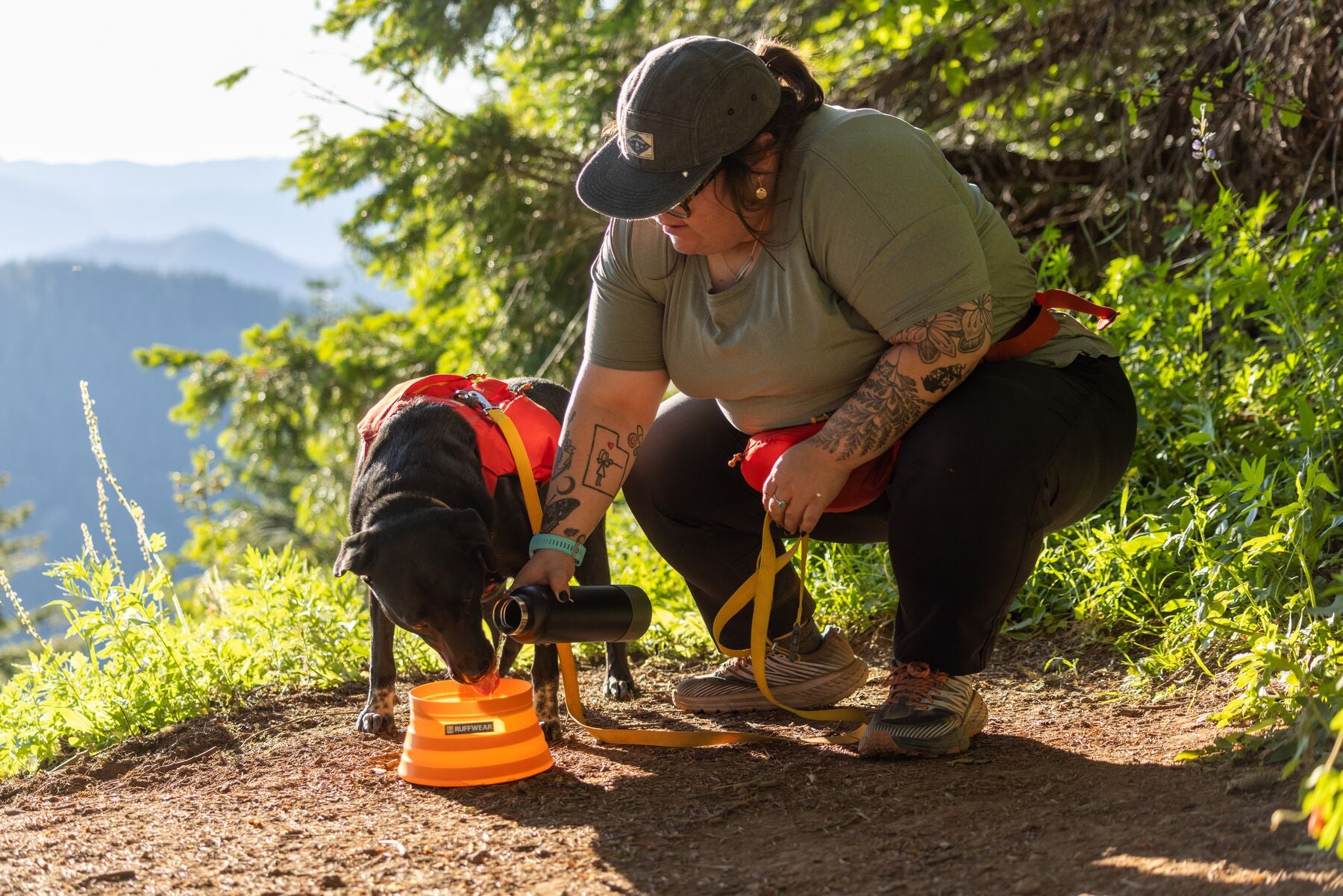 Woman pours water into a bowl for her dog on a trail
