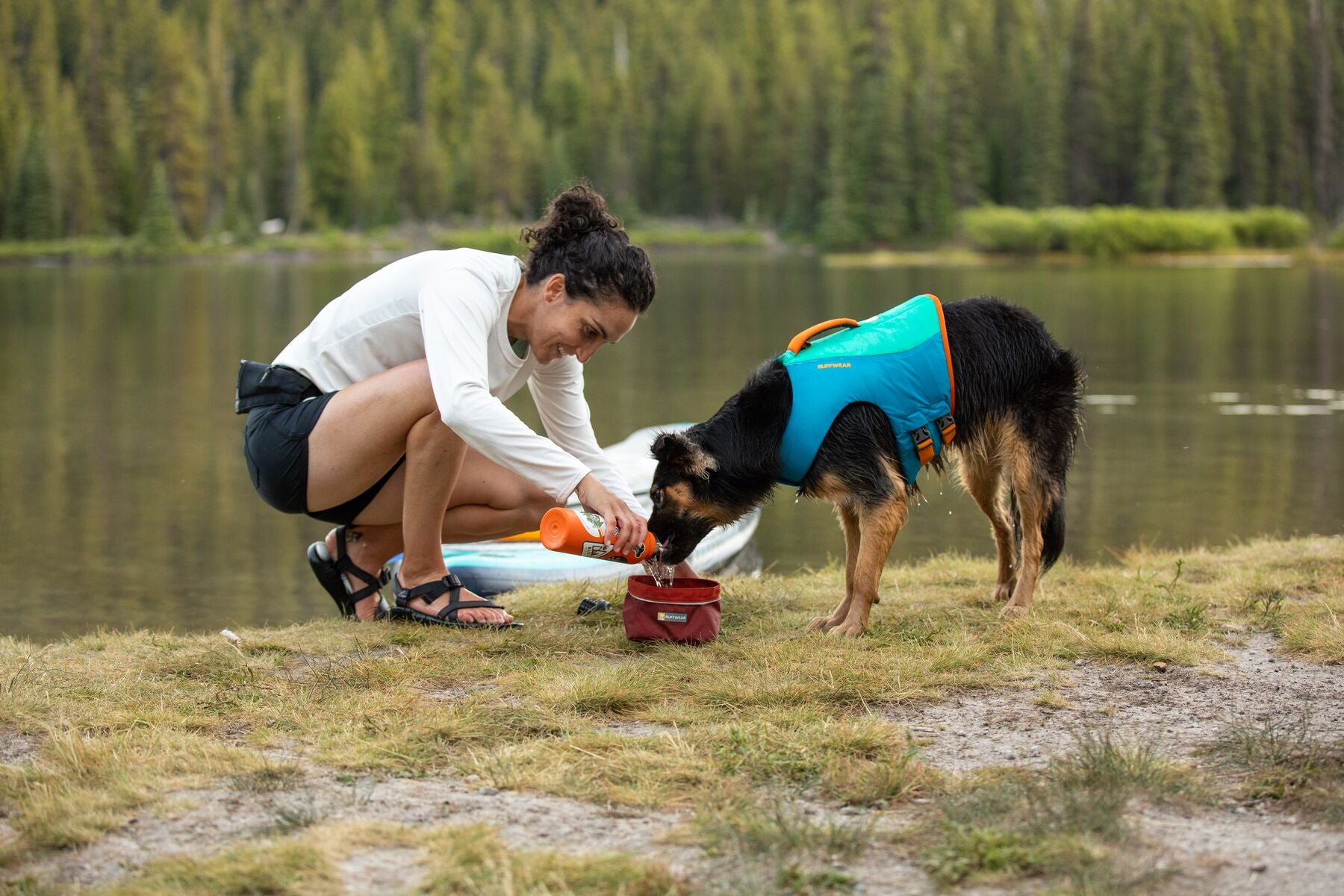 Woman pouring water into a bowl for her dog next to a lake